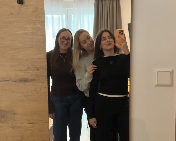 Drei Mädchen stehen vor einem Spiegel und machen mit dem Handy ein Foto von sich.