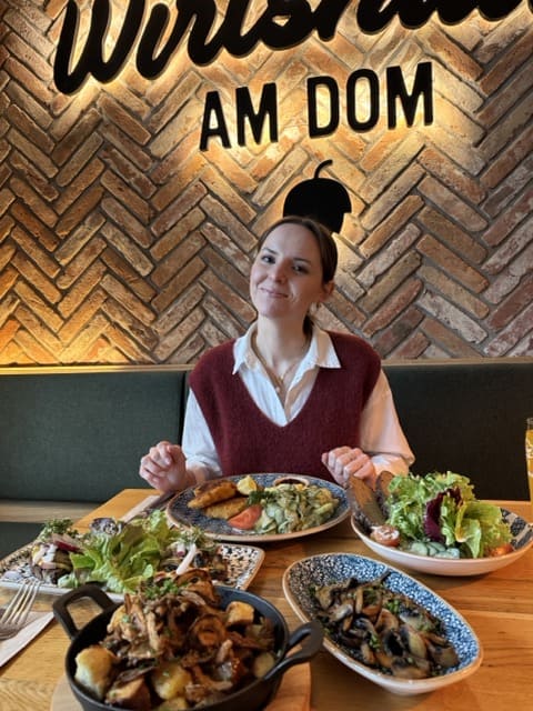 Frau sitzt im Wirtshaus am Dom vor ihrem Teller